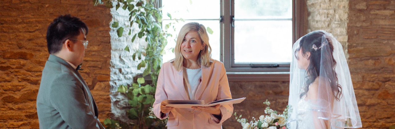 A celebrant reading a ceremony with a bride and groom