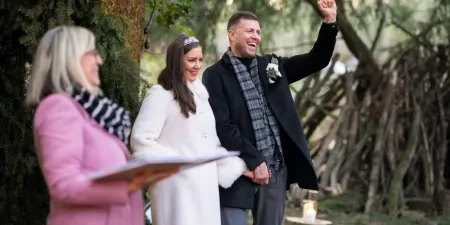 A celebrant with the bride and groom smiling