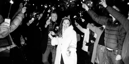 A bride and groom walking through raised sparklers