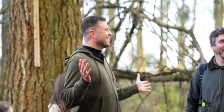 A man stood in a woodland with his arms apart