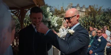 The bride's father places a cord over the couples hands in a handfasting ritual.