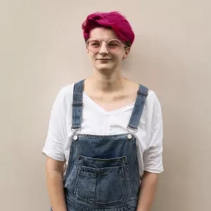 The front view a person wearing rompers and pink hair